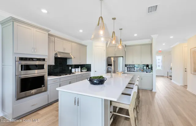 a kitchen with stainless steel appliances a stove a sink a microwave a refrigerator and white cabinets