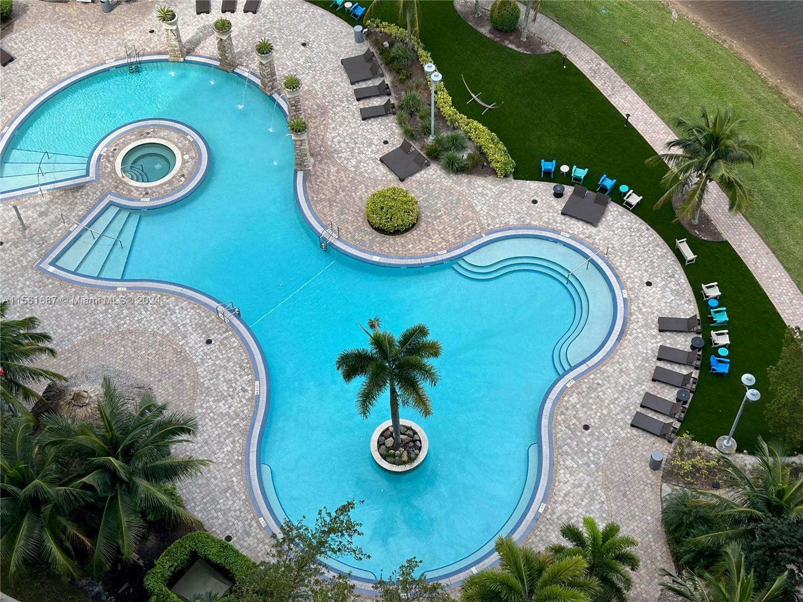 an aerial view of a swimming pool with outdoor seating and yard