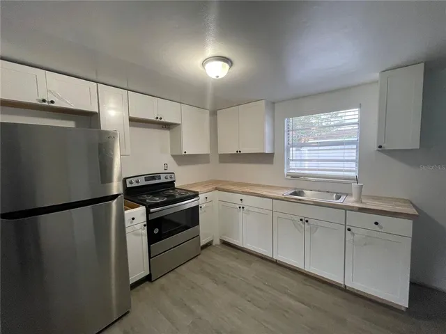 a kitchen with granite countertop a refrigerator sink and cabinets
