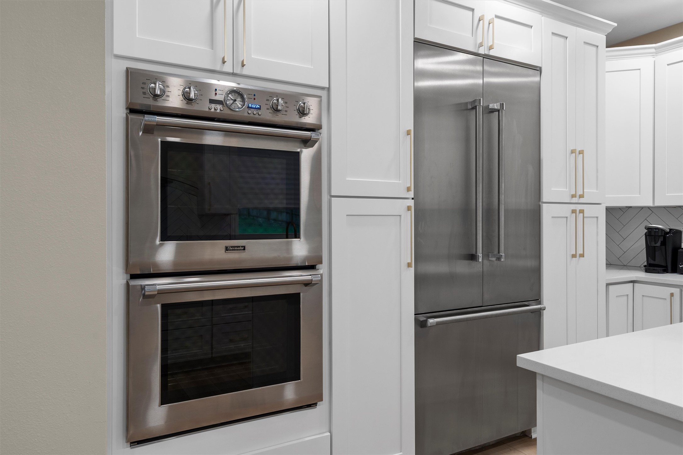 307 Hurst Creek Road Austin, TX 78734 - Photo 12 of 40 Gourmet kitchen featuring a stainless steel built-in double oven, coordinating stainless steel French door refrigerator, white shaker-style cabinetry with gold-tone hardware, and light-toned countertops