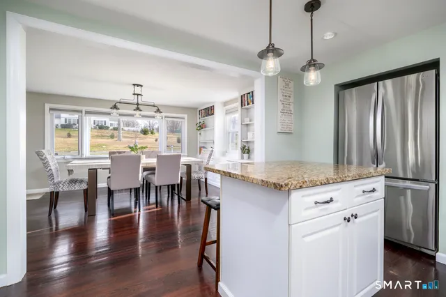 a kitchen with stainless steel appliances granite countertop a stove top oven a dining table and chairs with wooden floor