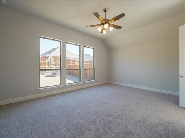 an empty room with chandelier fan and windows