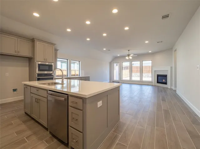 a kitchen with stainless steel appliances granite countertop a sink a stove and a wooden floors