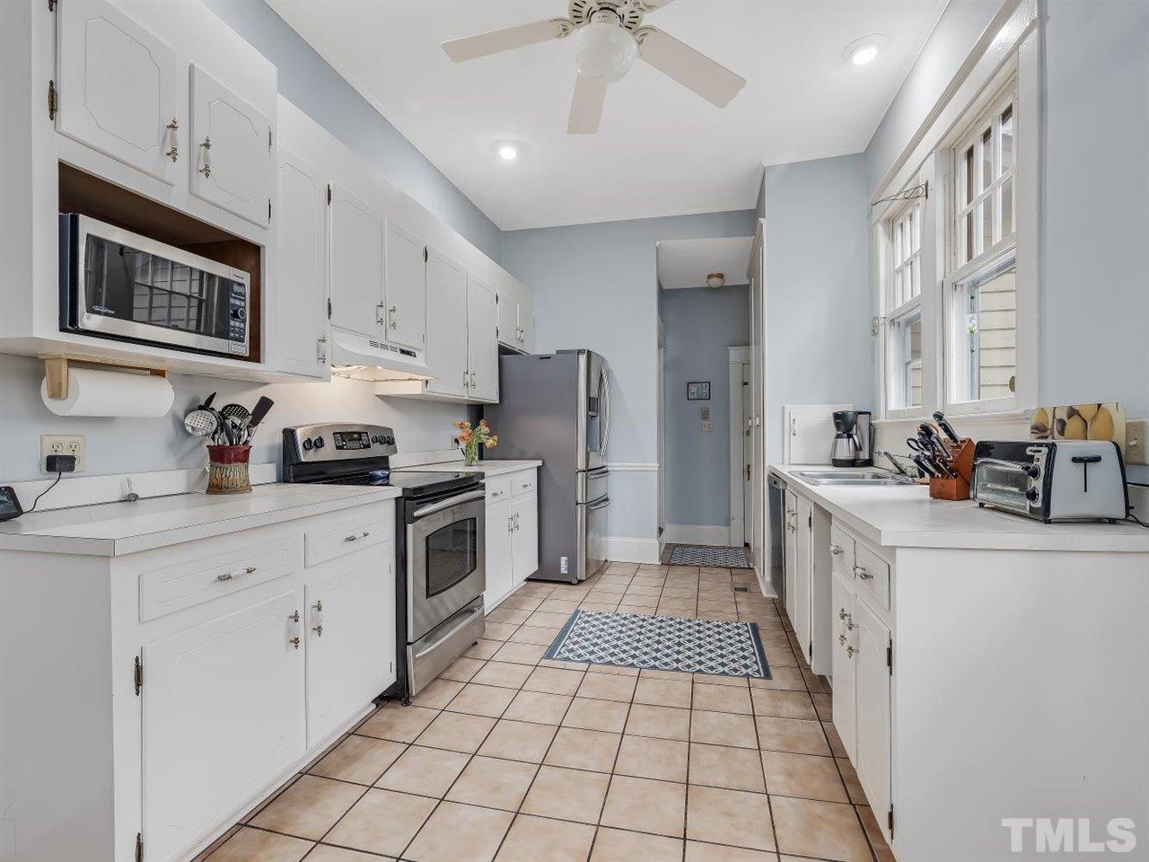 216 Hillcrest Road Raleigh, NC 27605 - Photo 16 of 49 a kitchen with white cabinets a sink stove and refrigerator