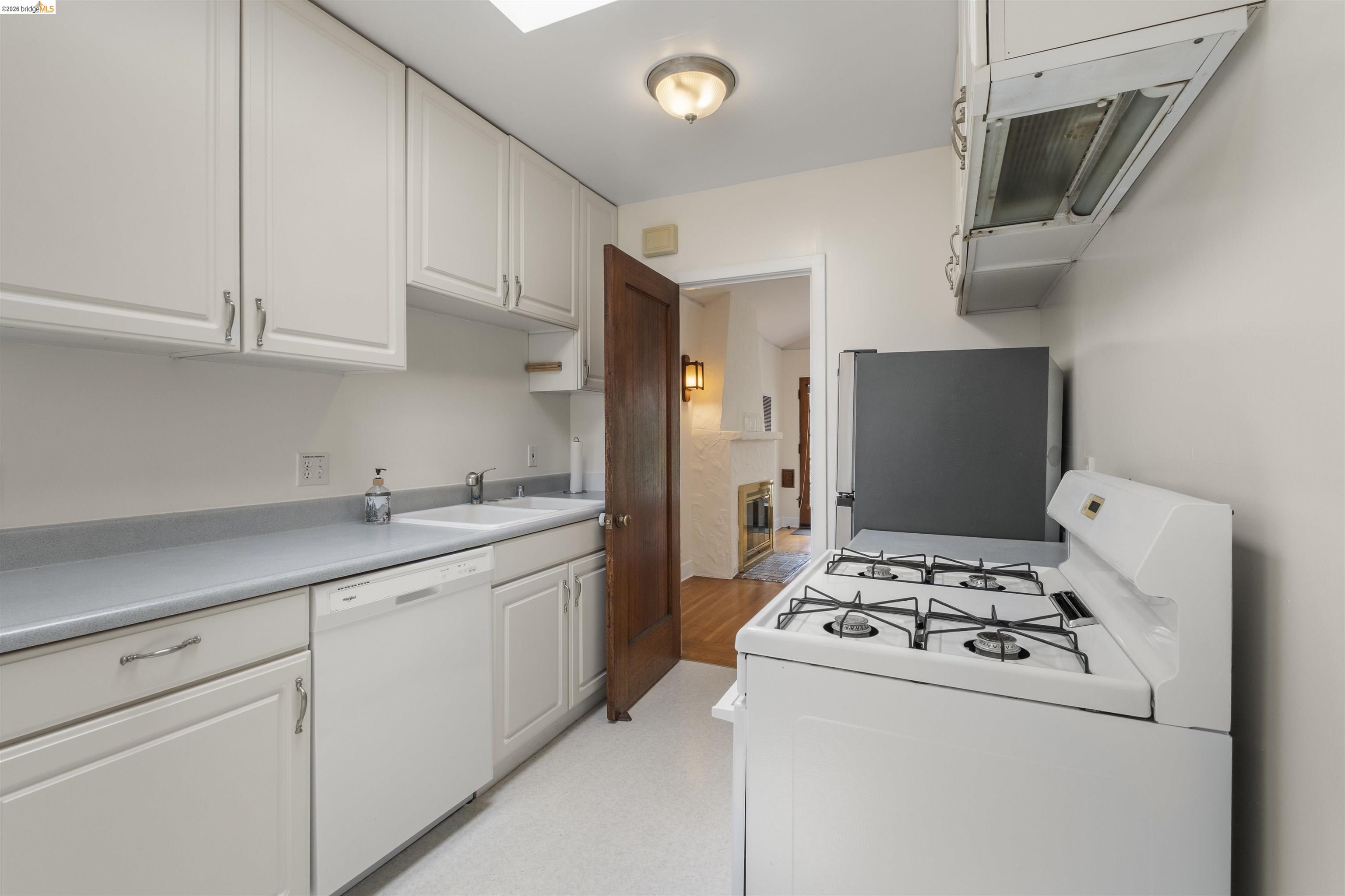 2444 Virginia Street, Unit B Berkeley, CA 94709 - Photo 25 of 39 Galley kitchen featuring white cabinetry, light countertops, a double basin sink, a dishwasher, and a gas range with an overhead vent hood