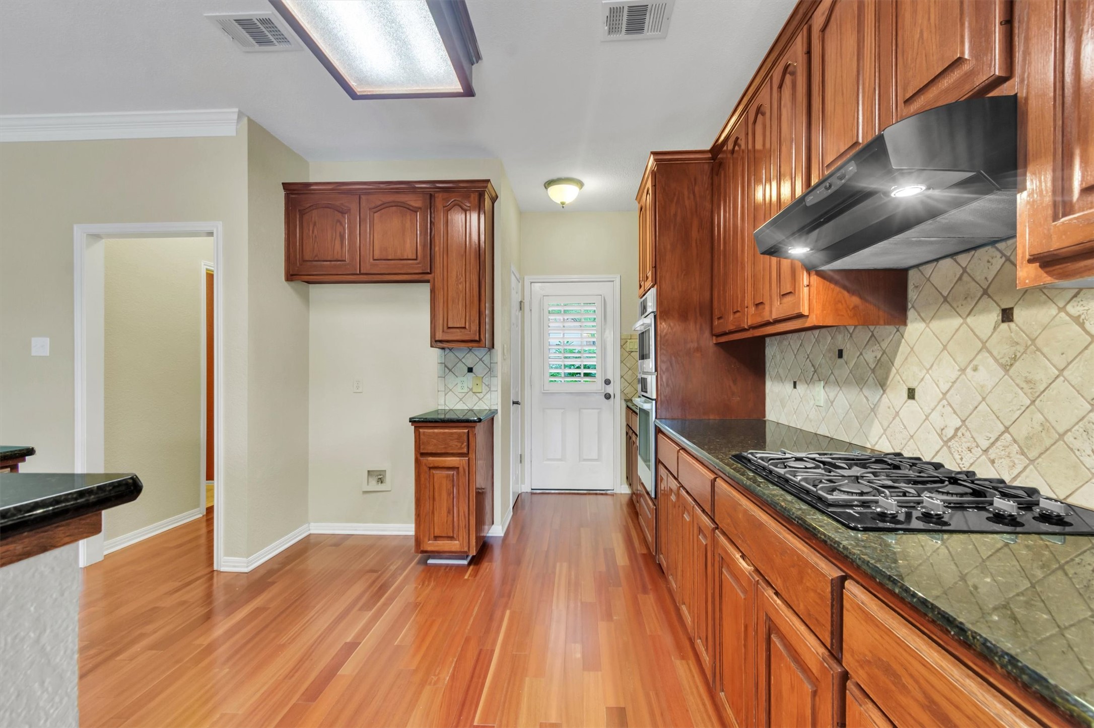 6008 Tributary Ridge Court Austin, TX 78759 - Photo 11 of 36 Rich hardwood floors complement cabinetry and granite countertops in this functional kitchen.