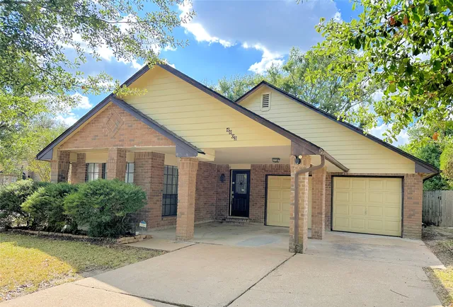 a view of a house with a yard plants and large tree