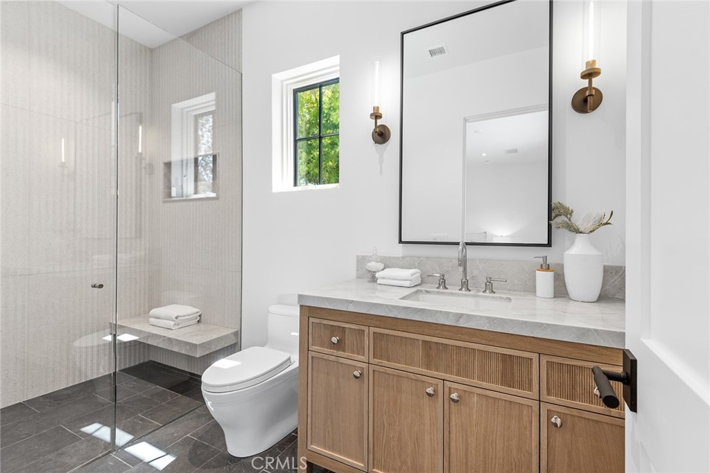 24044 Long Valley Road Hidden Hills, CA 91302 - Photo 42 of 57 a bathroom with a granite countertop toilet a sink and a mirror