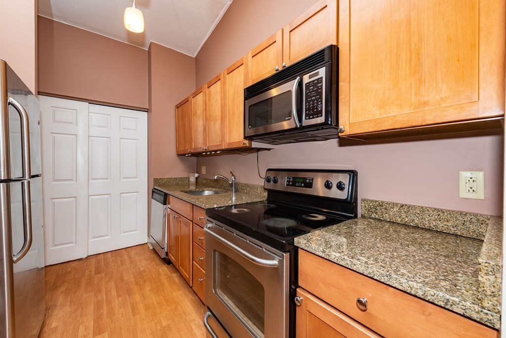 4 Raintree Circle, Unit 4D Brockton, MA 02302 - Photo 19 of 24 a kitchen with stainless steel appliances granite countertop a sink stove and microwave