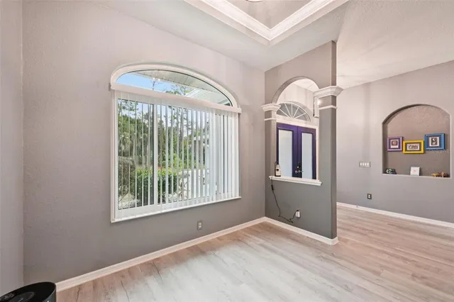 an empty room with wooden floor mirror and windows