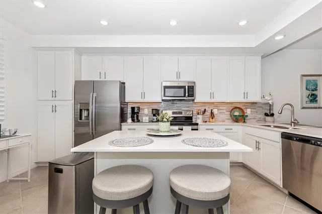 a kitchen with stainless steel appliances granite countertop a sink a stove a refrigerator cabinets and chairs