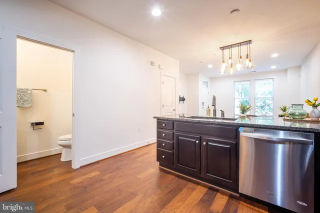 a kitchen with granite countertop wooden floors a refrigerator and a stove top oven