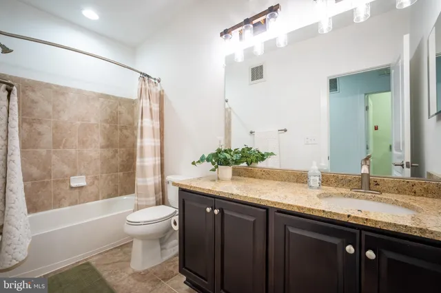 a spacious bathroom with a granite countertop sink a toilet and a shower