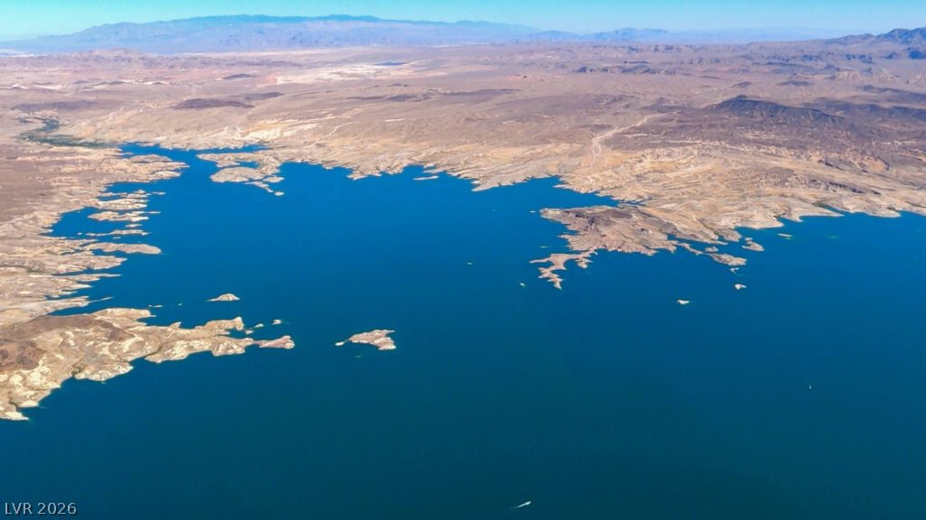 1140 Julie Road Henderson, NV 89002 - Photo 38 of 38 A vast expanse of water meets rugged, arid landscapes under a clear sky.