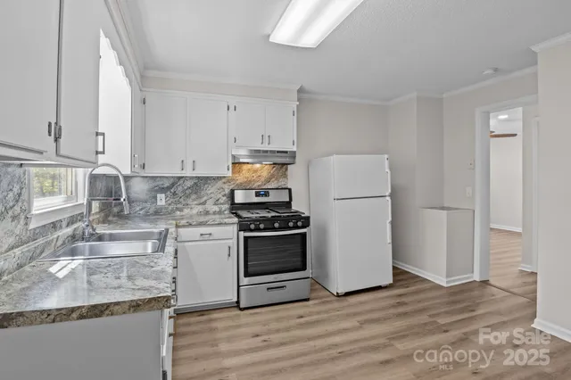 a kitchen with granite countertop a sink stove and refrigerator