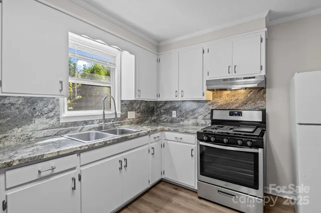 a kitchen with granite countertop a sink stove and cabinets