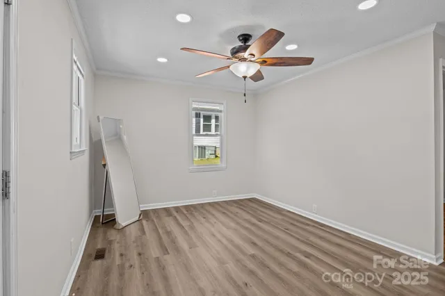 an empty room with wooden floor fan and windows