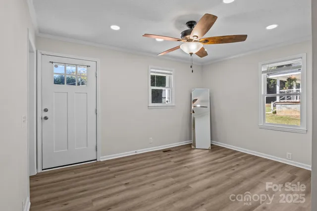 a view of an empty room with window and wooden floor