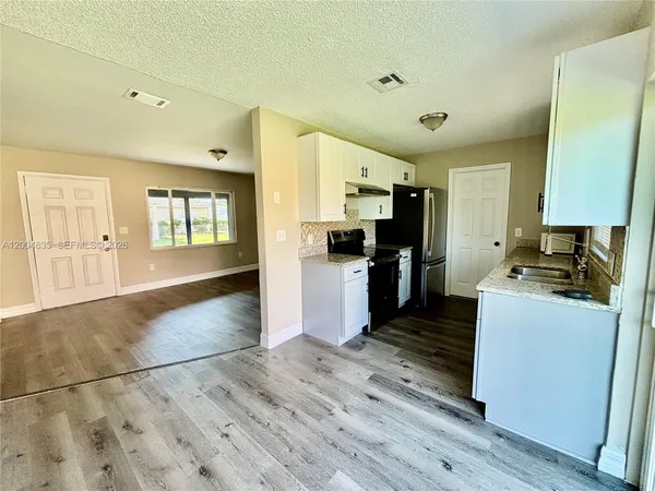 a kitchen with granite countertop a refrigerator and a stove top oven