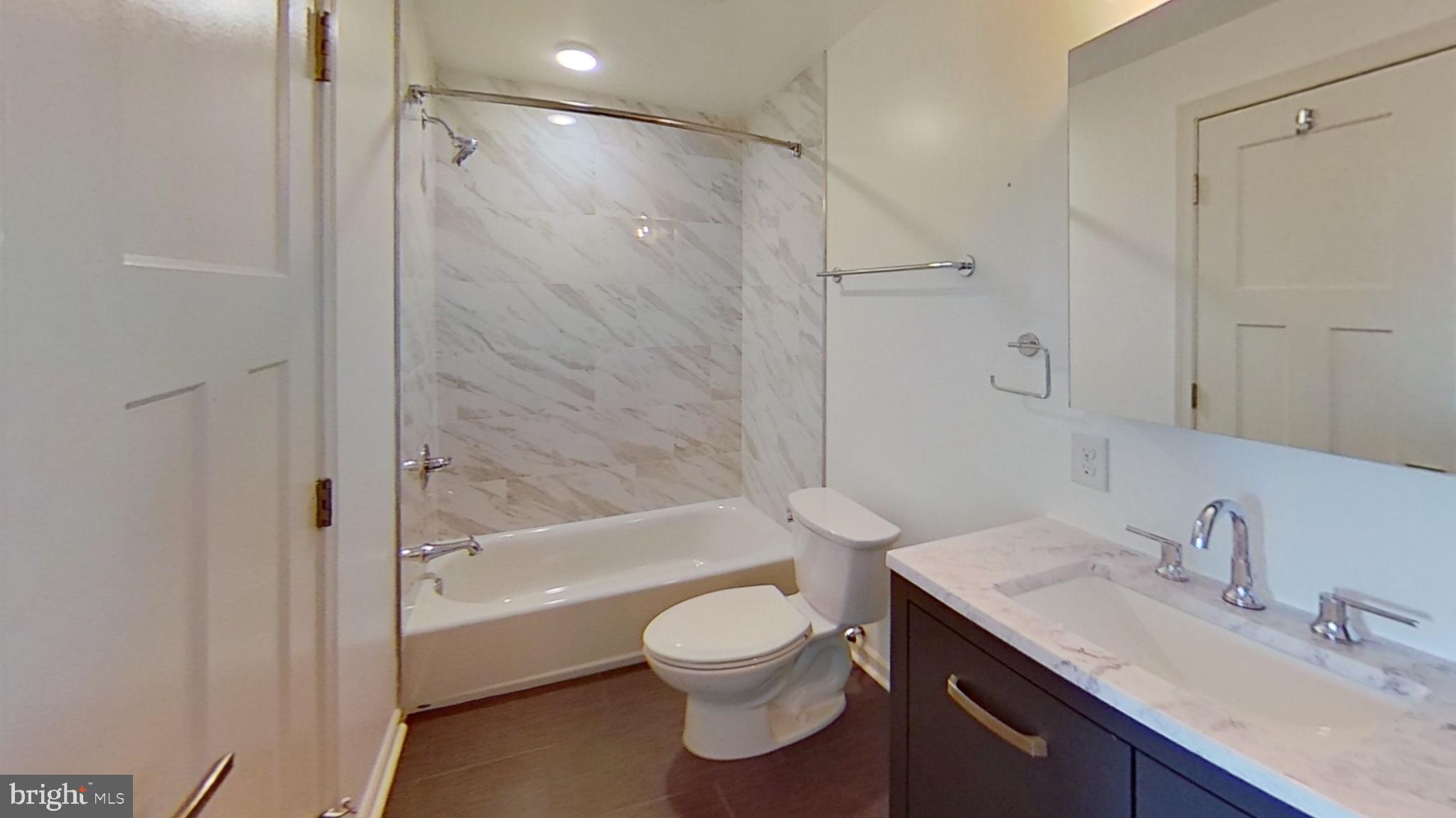 6778 Ridge Avenue, Unit 205 Philadelphia, PA 19128 - Photo 4 of 7 a bathroom with a granite countertop sink toilet a shower and a bathtub