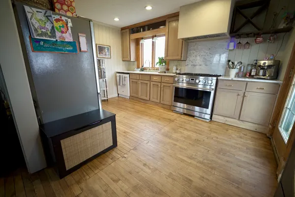 a kitchen with stainless steel appliances granite countertop a refrigerator a sink a stove and wooden floor