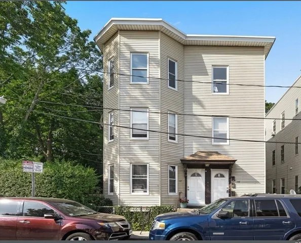 a front view of a building with cars parked