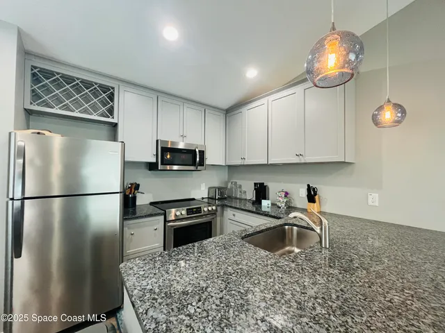 a kitchen with kitchen island granite countertop a stove a sink and a refrigerator
