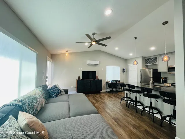 a living room with furniture kitchen view and a wooden floor