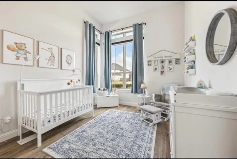 a room with a baby bed a couch and dresser