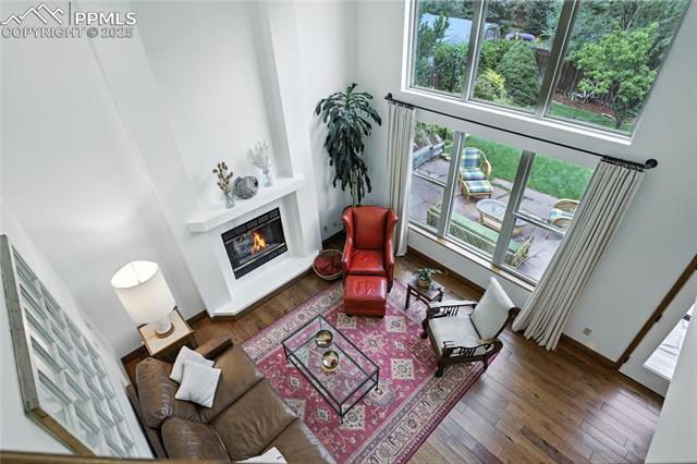 2130 Wickes Road Colorado Springs, CO 80919 - Photo 25 of 49 Living room featuring a glass covered fireplace, wood finished floors, and a high ceiling