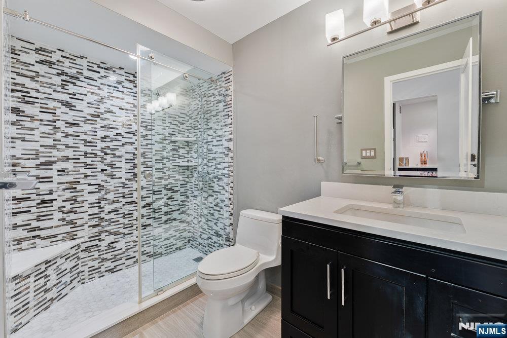 160 Overlook Avenue, Unit 20D Hackensack, NJ 07601 - Photo 11 of 22 a bathroom with a granite countertop toilet sink mirror and shower