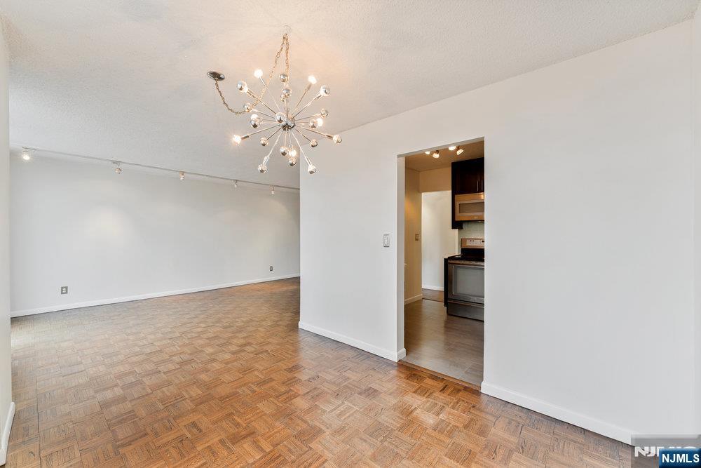 160 Overlook Avenue, Unit 20D Hackensack, NJ 07601 - Photo 6 of 22 an empty room with chandelier fan and kitchen view