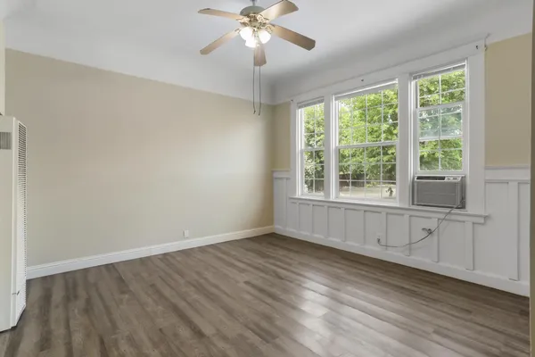 a view of an empty room with wooden floor and a window