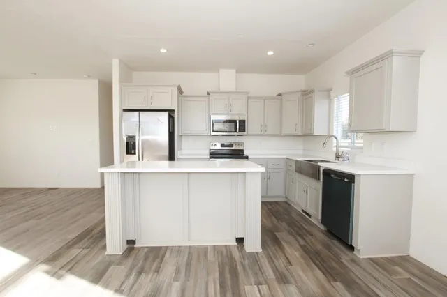 a kitchen with wooden floors white cabinets and appliances