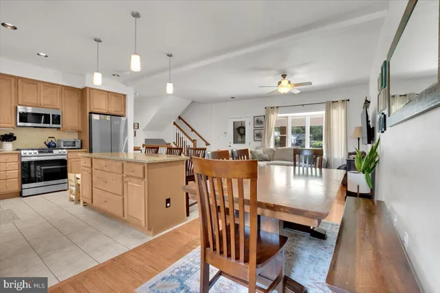 a kitchen with stainless steel appliances kitchen island granite countertop a stove a refrigerator a kitchen island a dining table and chairs with wooden floor