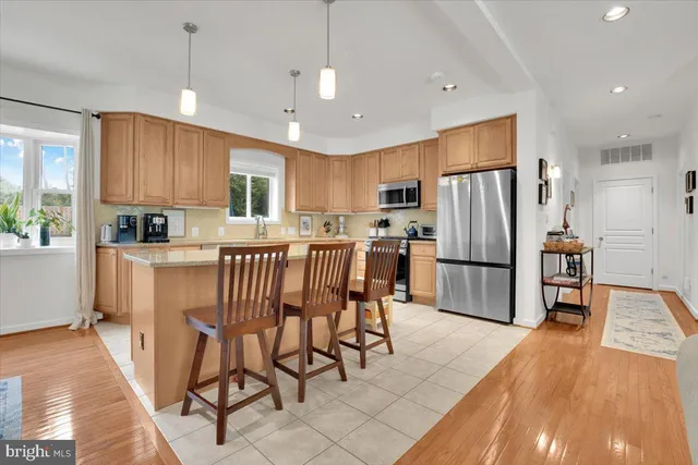 a kitchen with stainless steel appliances a refrigerator a stove a sink a dining table and chairs with wooden floor