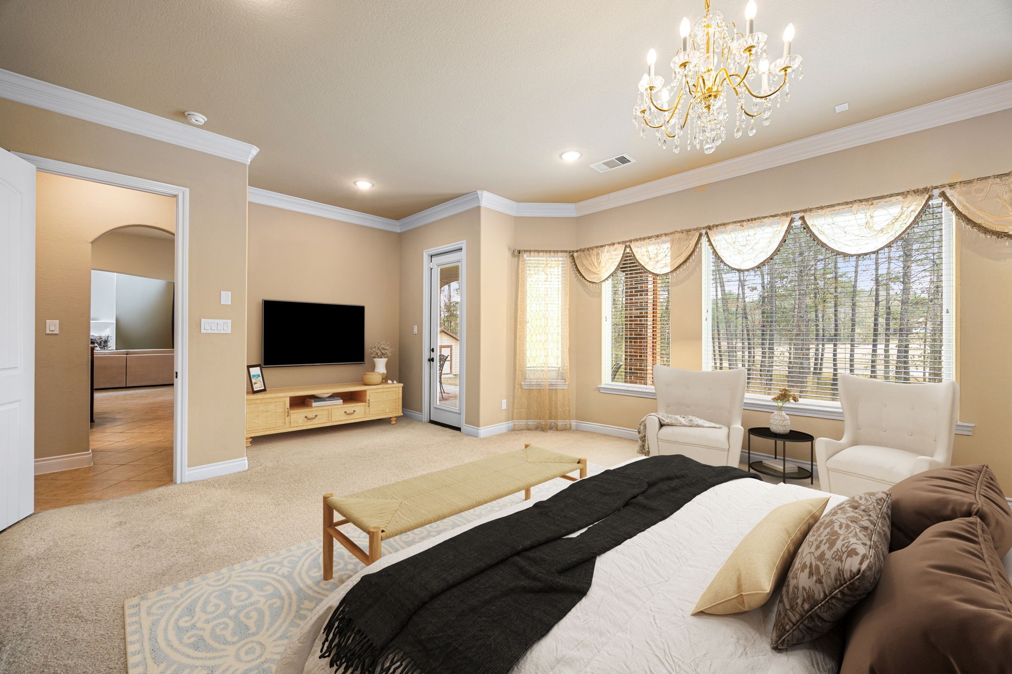 23421 Cannondale Loop Montgomery, TX 77316 - Photo 17 of 47 Bright and inviting primary bedroom showcasing plush carpeting, crown molding, and a stunning chandelier that adds a touch of elegance. Large windows fill the space with natural light, while a private sitting area creates a peaceful retreat ideal for reading, relaxing, or enjoying a quiet morning coffee. Neutral tones throughout provide a calm, sophisticated atmosphere with timeless appeal.