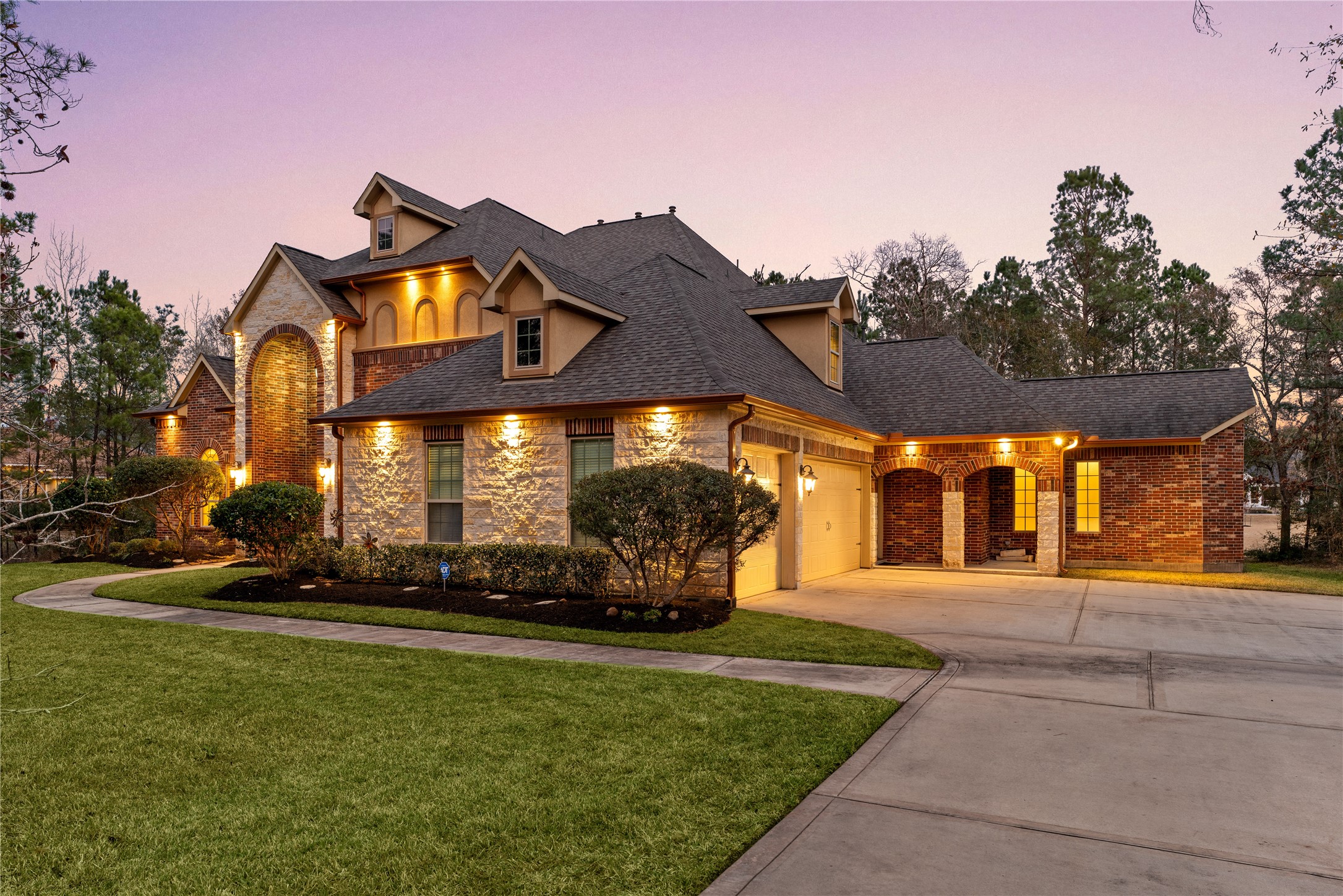 23421 Cannondale Loop Montgomery, TX 77316 - Photo 2 of 47 Beautiful curb appeal welcomes you with a stunning brick and stone exterior, warm exterior lighting, and a charming covered entry. This impressive home offers 5 bedrooms, 4 full bathrooms, and 2 half baths, combining elegance, space, and comfort perfect for everyday living and entertaining.