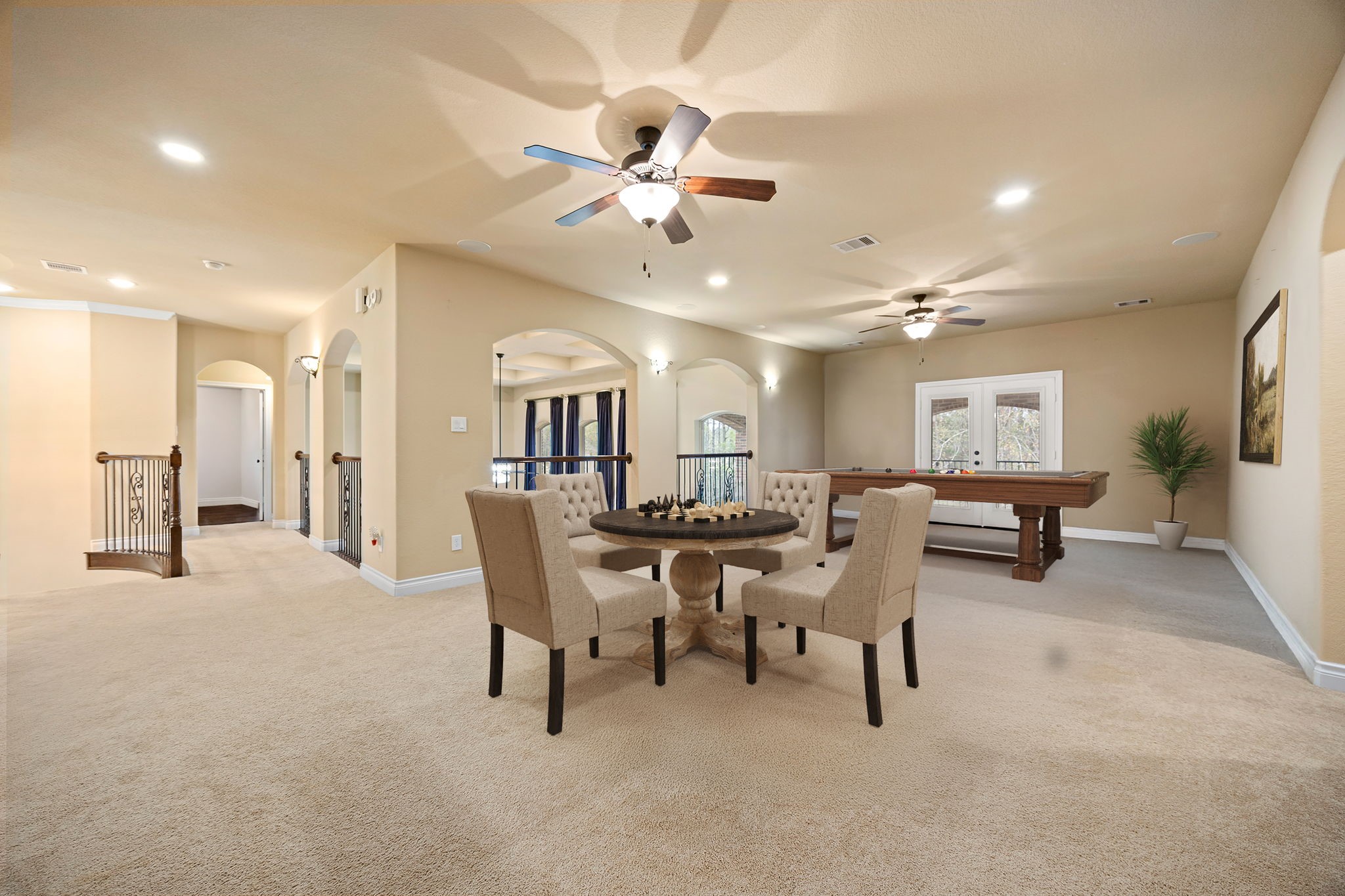 23421 Cannondale Loop Montgomery, TX 77316 - Photo 23 of 47 Spacious upstairs game room designed for both relaxation and entertainment, featuring plush carpet, recessed lighting, and multiple ceiling fans for added comfort. The open layout easily accommodates a seating area, game table, and billiards space, while large windows and French doors bring in natural light and offer a pleasant view. Perfect for hosting game nights, family gatherings, or creating a versatile media and lounge area.