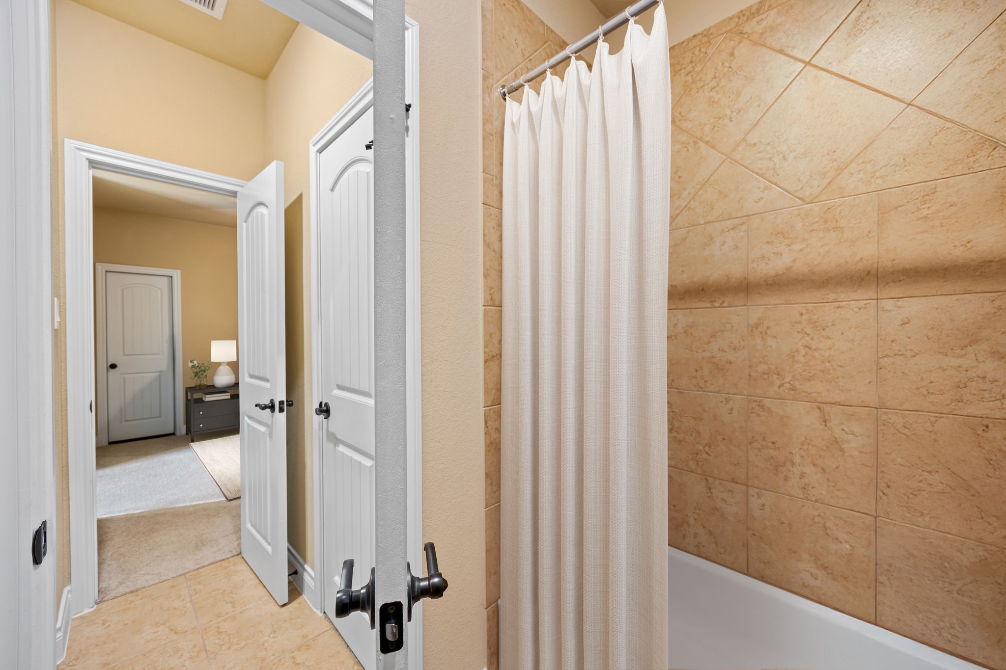 23421 Cannondale Loop Montgomery, TX 77316 - Photo 29 of 47 Spacious jack-and-jill bathroom with a tiled tub/shower combination, clean lines, and a soft neutral color palette. The layout offers easy access from the bedroom, creating a functional and comfortable space ideal for everyday living or guests.
