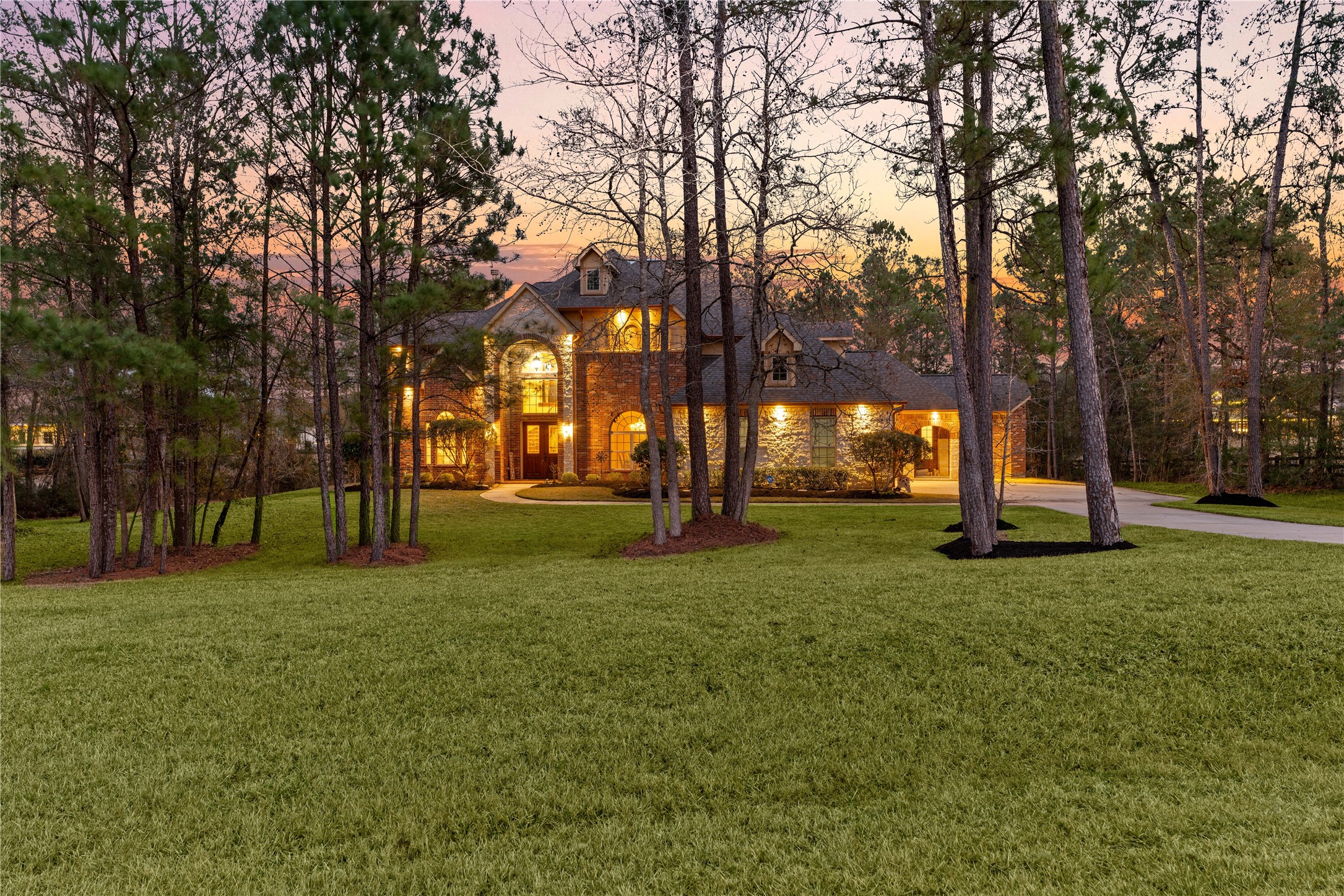 23421 Cannondale Loop Montgomery, TX 77316 - Photo 3 of 47 Grand residence set on a beautifully landscaped, tree-lined lot, showcasing timeless architecture and a serene, park-like atmosphere. The illuminated exterior, expansive lawn, and private surroundings create an inviting retreat that feels both impressive and tranquil. A truly special place to call home.