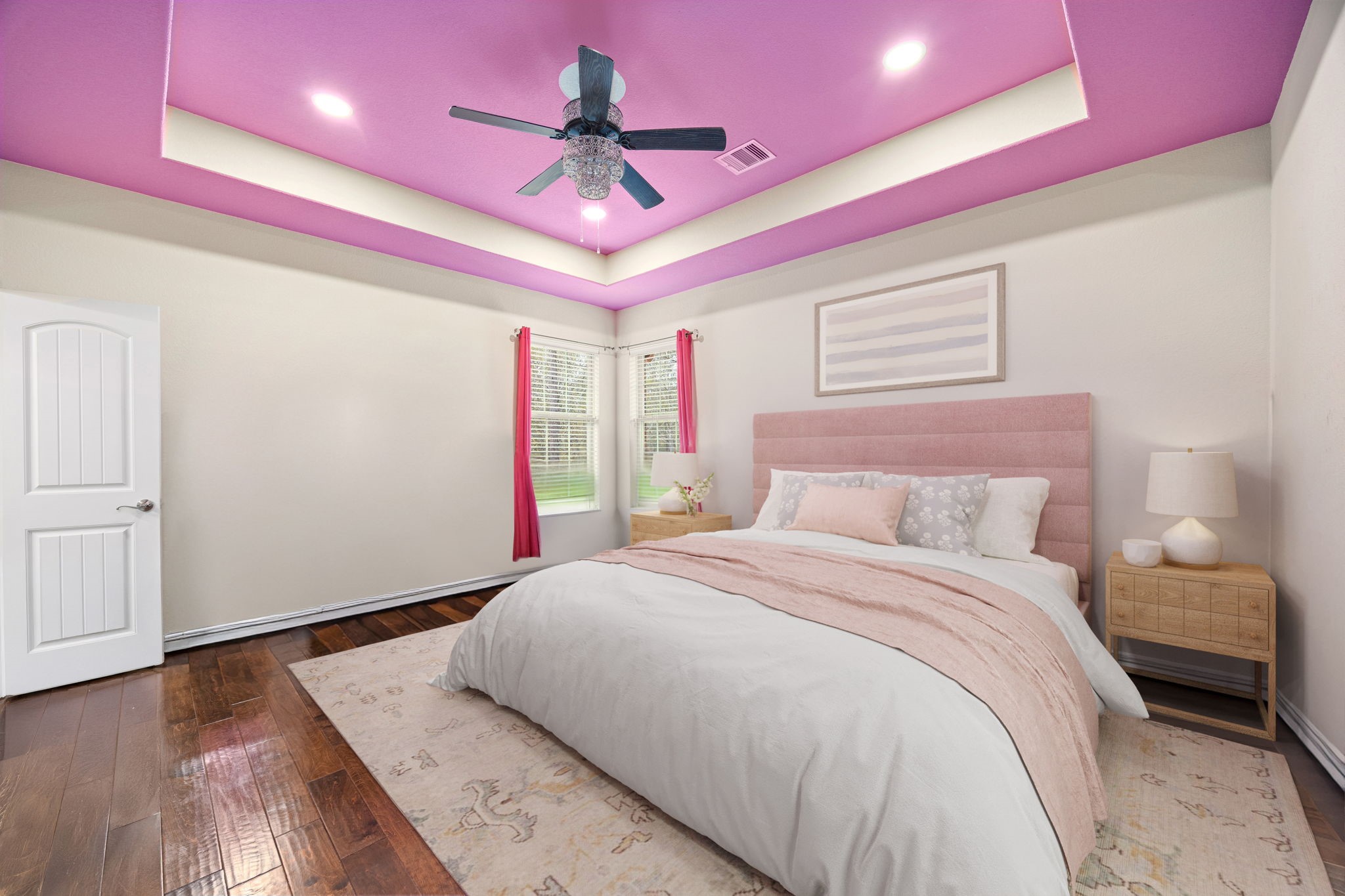 23421 Cannondale Loop Montgomery, TX 77316 - Photo 31 of 47 Bright and cheerful bedroom showcasing a striking tray ceiling, recessed lighting, and a stylish ceiling fan with crystal detail. Warm wood floors, soft neutral walls, and a plush area rug create a cozy foundation, while large windows bring in beautiful natural light. Finished with a padded headboard, matching nightstands, and modern décor for a fresh, inviting feel.