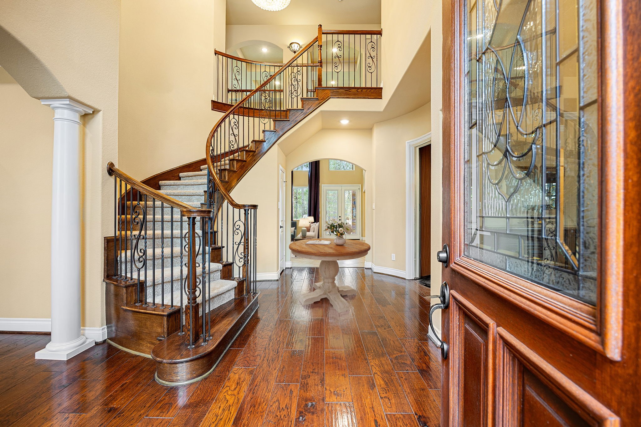 23421 Cannondale Loop Montgomery, TX 77316 - Photo 4 of 47 A breathtaking grand entry welcomes you with rich hardwood floors, soaring ceilings, and a stunning curved staircase accented with wrought iron balusters and warm wood railings. The open, airy layout flows beautifully into the main living spaces, creating a dramatic yet inviting first impression that sets the tone for the elegance and comfort found throughout the home.
