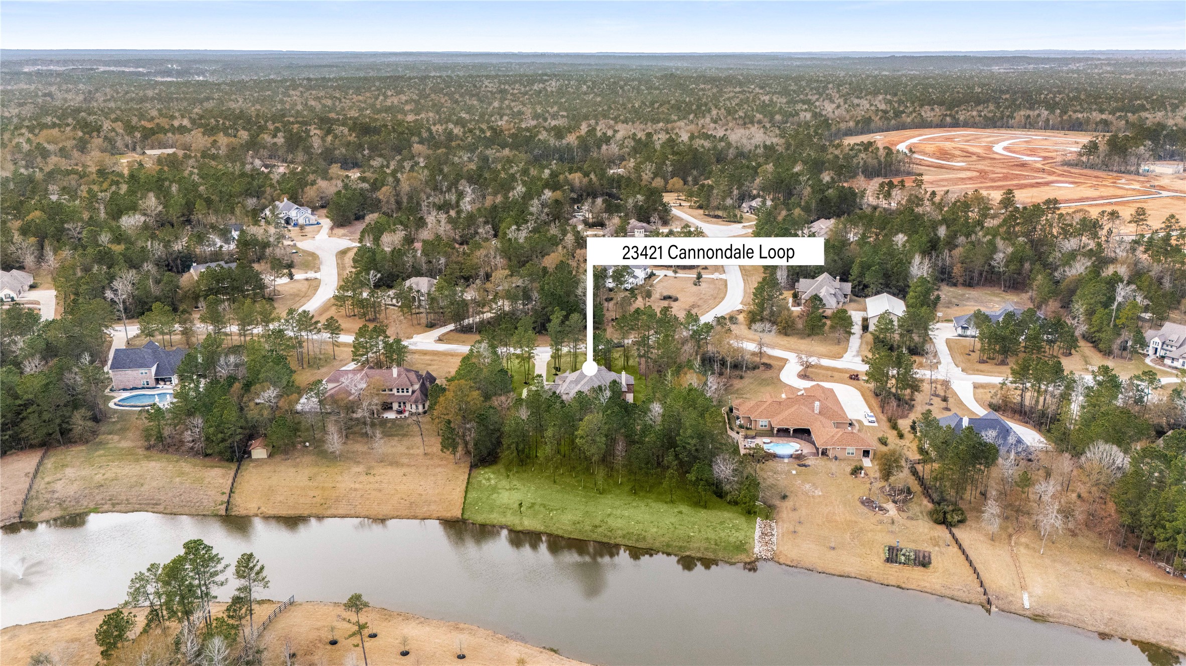 23421 Cannondale Loop Montgomery, TX 77316 - Photo 41 of 47 Aerial perspective showcasing the home’s prime location on a quiet loop with a scenic lake behind the property. Surrounded by mature trees and neighboring estate homes, this setting offers a desirable balance of privacy, open space, and community living, with convenient access to nearby amenities and main roads.