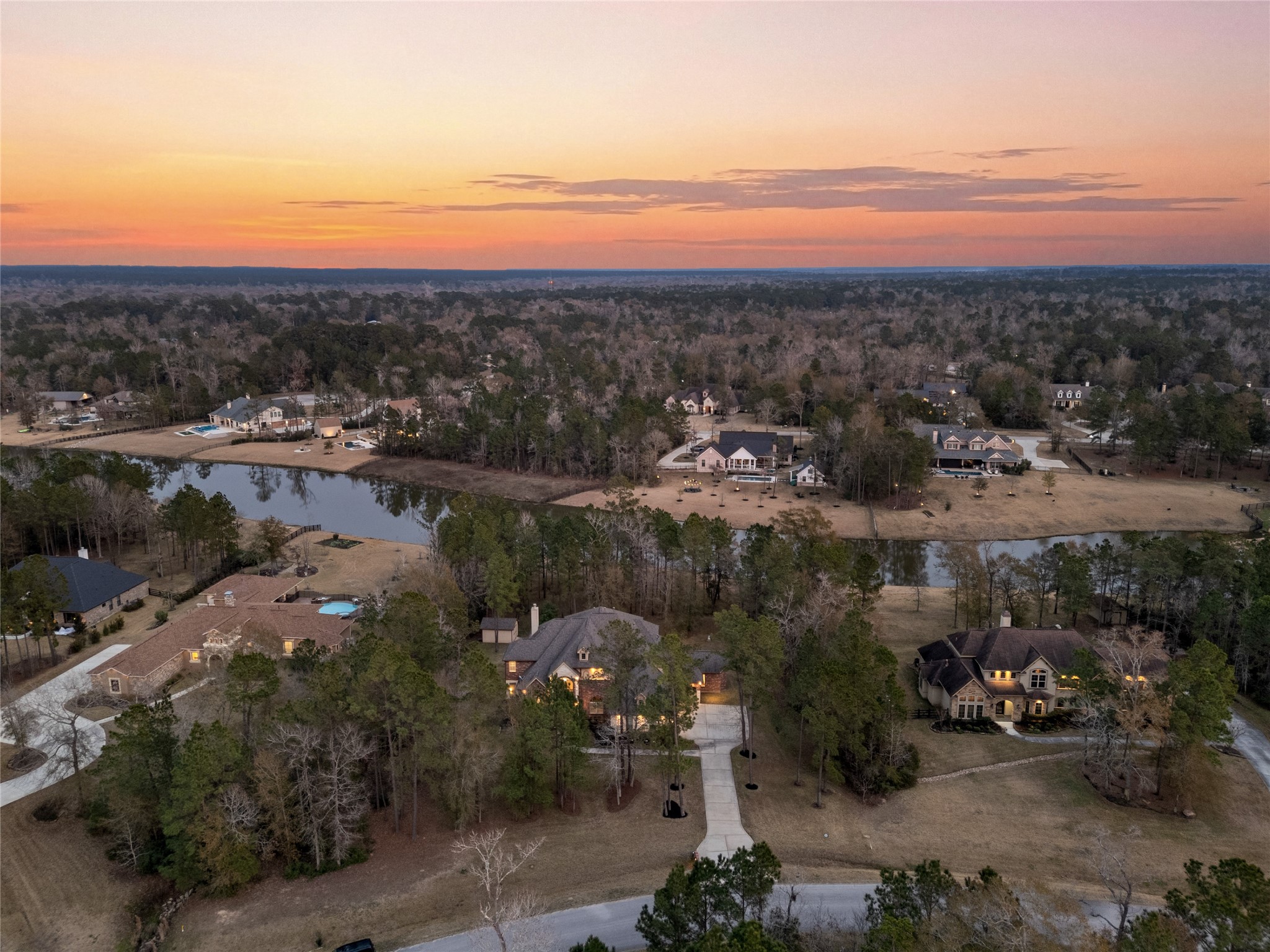 23421 Cannondale Loop Montgomery, TX 77316 - Photo 42 of 47 Breathtaking sunset aerial showcasing the property nestled among mature trees with tranquil water views and neighboring estate homes. Enjoy a peaceful, private setting with scenic surroundings, while still being conveniently located near shopping, dining, and major roadways.
