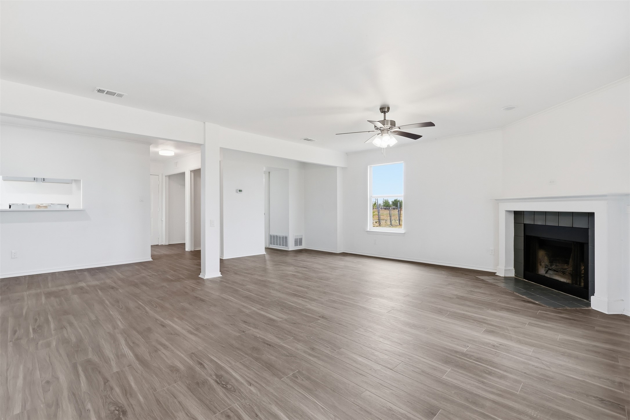 13201 Jacobson Road Manor, TX 78653 - Photo 9 of 25 an empty room with wooden floor fireplace and windows