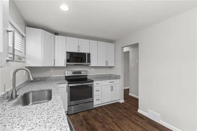 a kitchen with stainless steel appliances granite countertop a sink stove and microwave