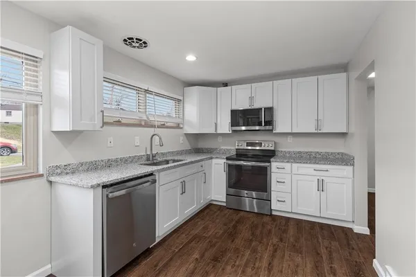 a kitchen with granite countertop a sink cabinets and stainless steel appliances