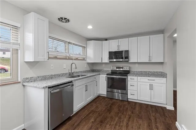 a kitchen with granite countertop a sink cabinets and stainless steel appliances