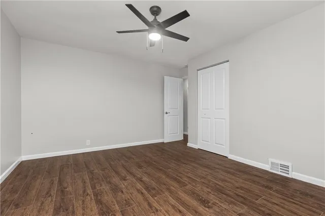 an empty room with wooden floor and ceiling fan